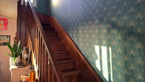 A staircase with wooden railings leading to a landing area with a patterned wall and a framed picture.