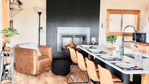 A modern kitchen with a central island, wooden cabinets, and a built-in fireplace. - Romantic Lakeview Cabin | Hot Tub + Incredible Views (Divide)