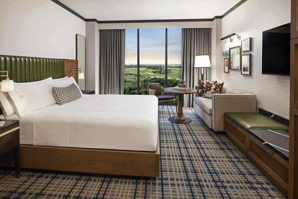 A hotel room with a large bed, a seating area with a table, and a TV.