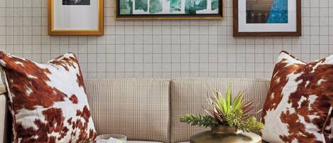 Un salon avec un canapé, une table basse et des œuvres d’art encadrées accrochées au mur.