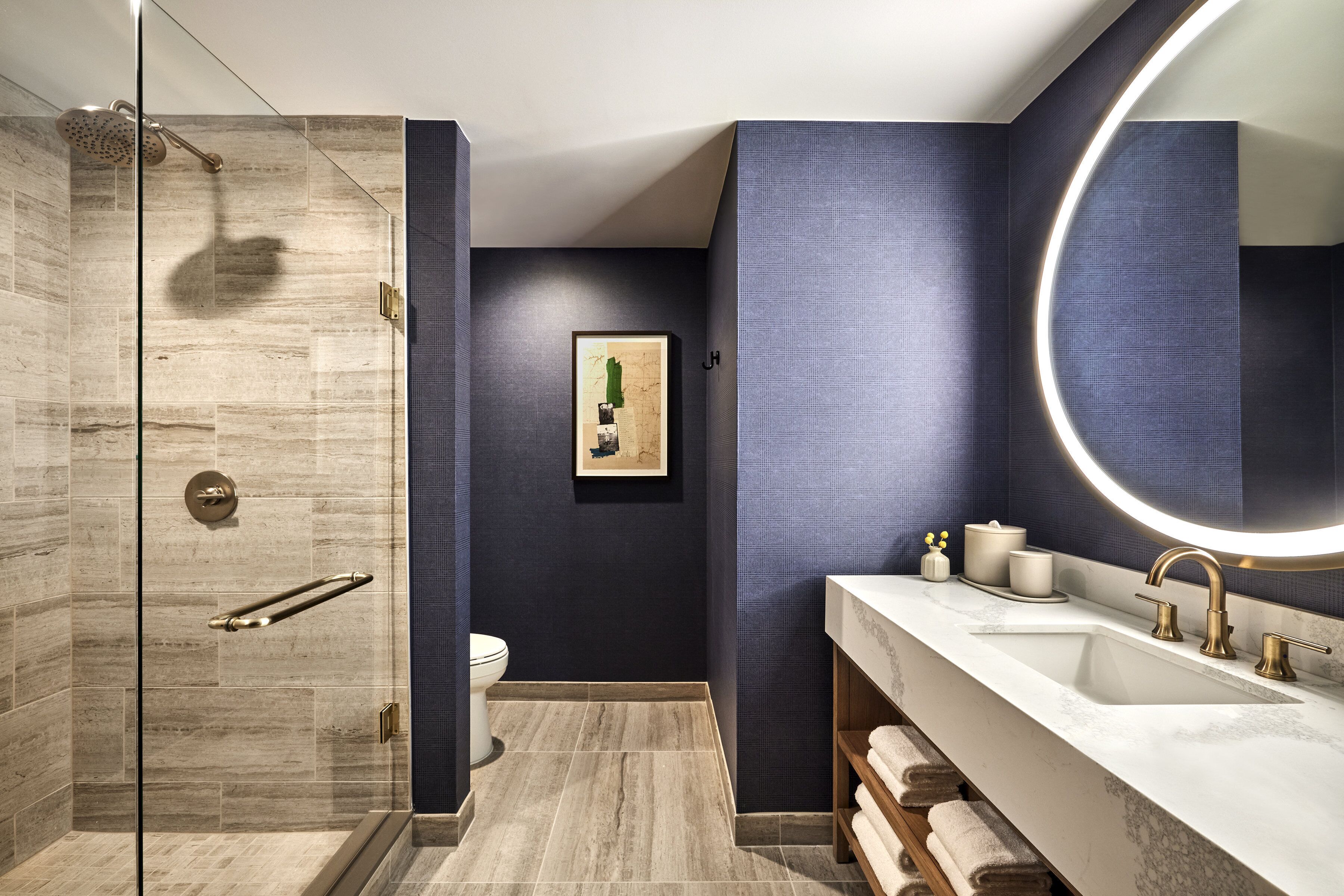 A modern bathroom with a glass shower enclosure, a large mirror, and a vanity with a sink and towel rack.