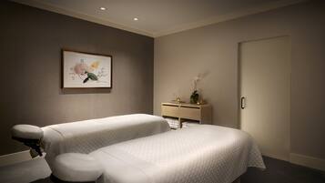 A room with two beds, a bedside table, a framed picture on the wall, and a door.