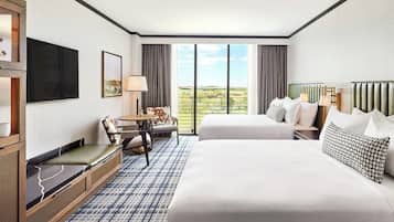A hotel room with a large bed, a sofa, a TV, and a balcony with a view of the countryside.