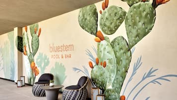 A cactus-themed wall mural with seating and tables in a lounge area.