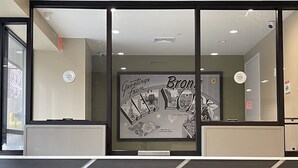 A reception area with a framed welcome sign, a security camera, and a fire alarm panel.