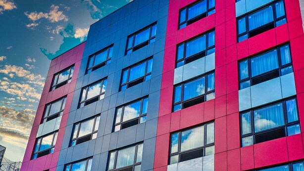 A modern building with a multi-colored facade, large windows, and a clear sky.