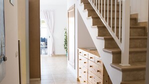 Un passadís amb una escala de fusta, un armari de fusta i una porta que dona a una altra habitació.