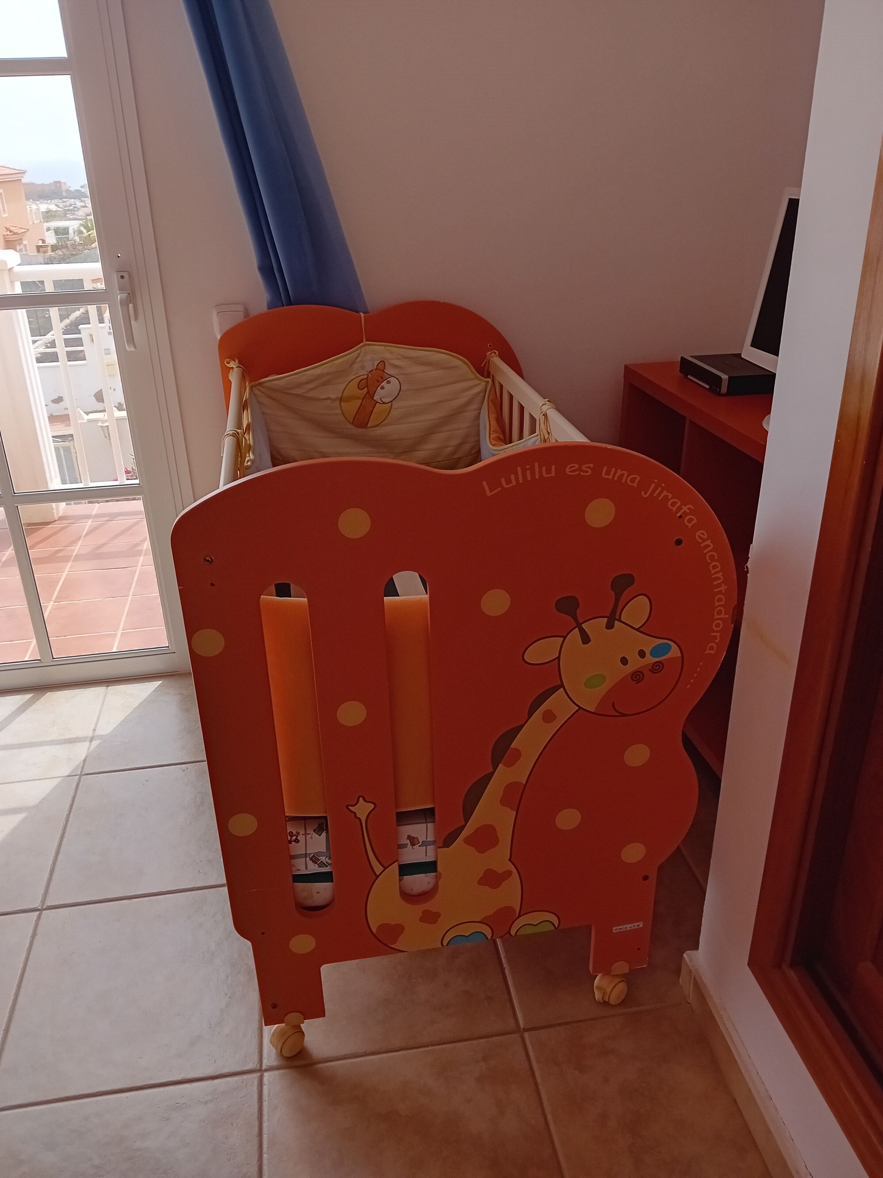A child's bed with giraffe-themed headboard and a window view.