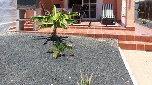 Una casa de dues plantes amb un balcó, antena parabòlica i pati amb taula i cadires.
