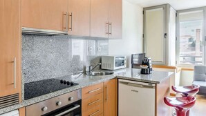 A compact kitchen with granite countertops, a built-in microwave, a coffee maker, and a dishwasher. - Bright Quiet Flat | Terrace by HostWise (Porto)