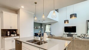 Een moderne keuken met een centraal eiland, witte kasten en hanglampen.