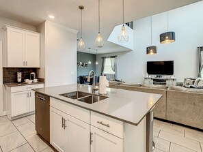 A modern kitchen with a central island, white cabinetry, and pendant lighting.