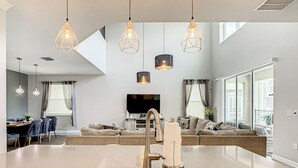Een moderne keuken met een centraal eiland, een RVS-gootsteen en hanglampen.