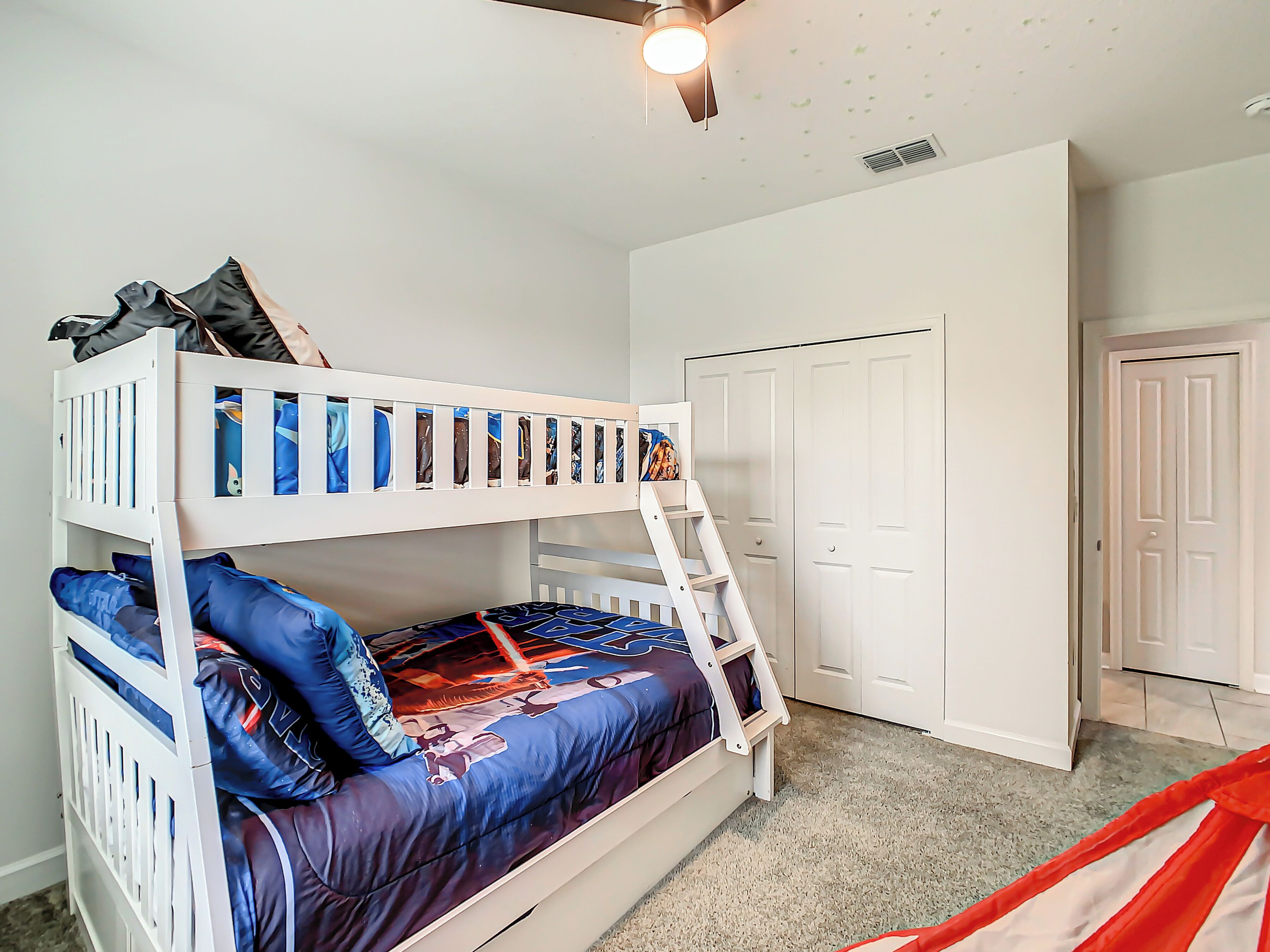 A bunk bed with a ladder, a wardrobe, and a door in a bedroom.