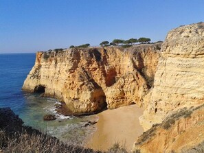 Eine Küstenklippe mit Strand und klarem, blauem Meer.