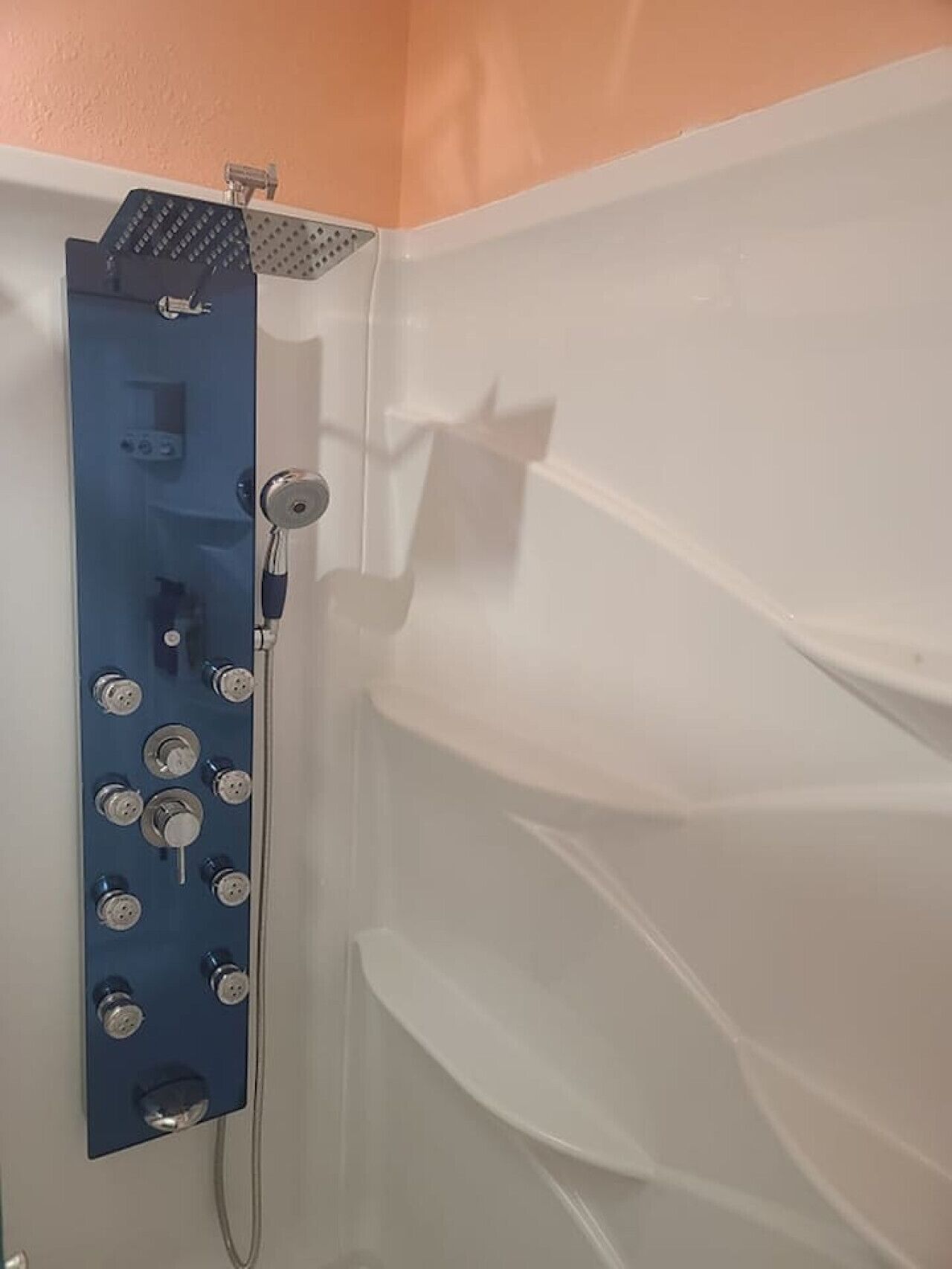 A shower with multiple controls and a handheld showerhead.