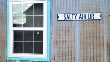 A corrugated metal building with a window and a street sign reading "SALTY AIR DR".