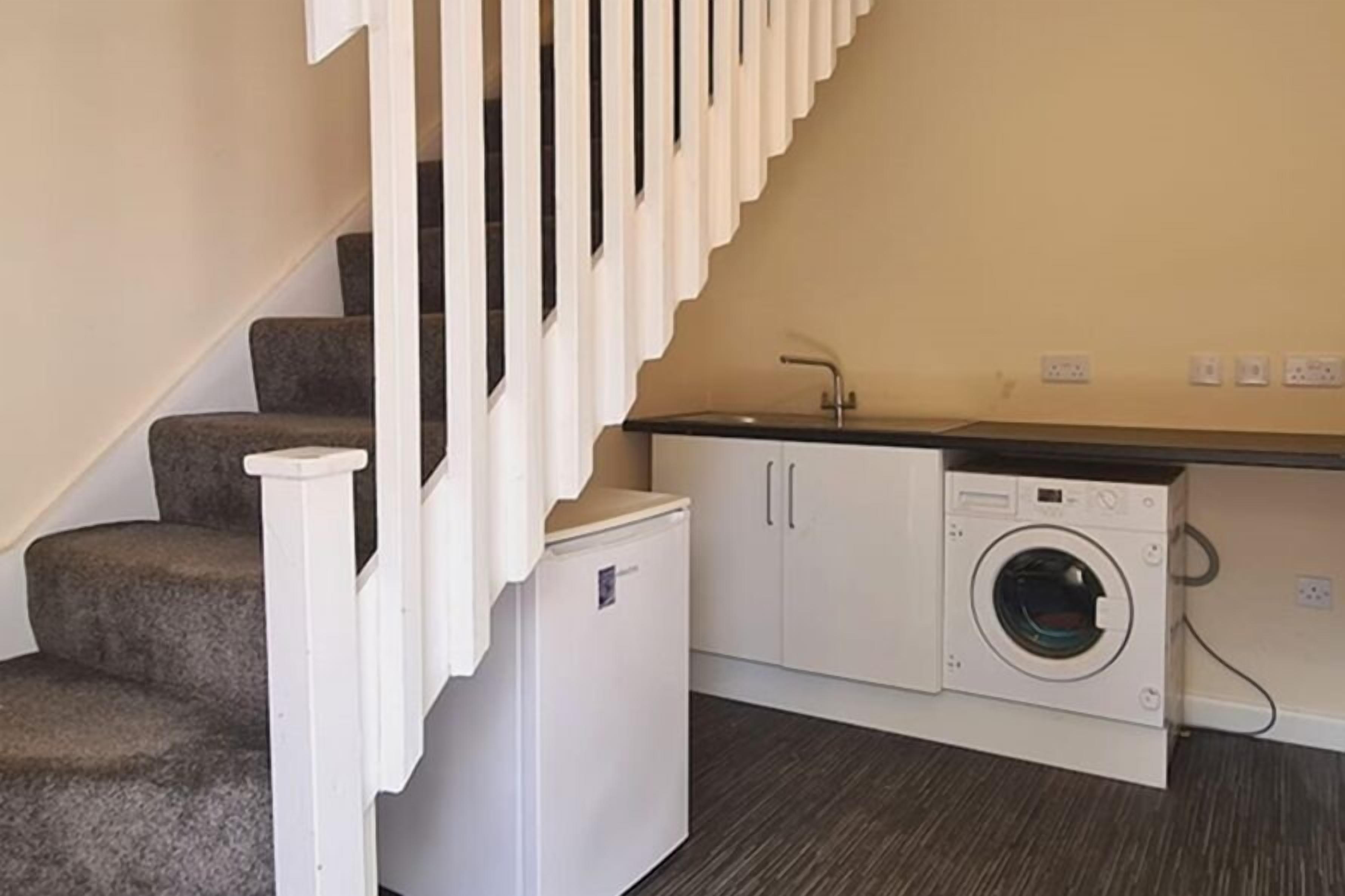 A laundry area with a washing machine, a dryer, and a small refrigerator.