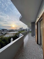 A balcony with a view of the cityscape and sunset.
