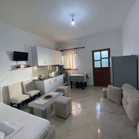 A compact living space with a kitchenette, a dining area, and a seating area with a sofa and chairs.