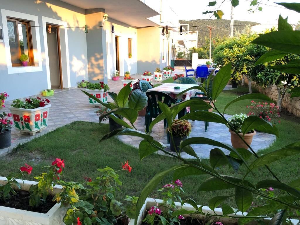 Un patio con mesas al aire libre, plantas en macetas y un sendero de piedra.