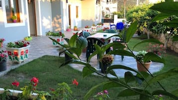 Un patio con mesas al aire libre, plantas en macetas y un sendero de piedra.