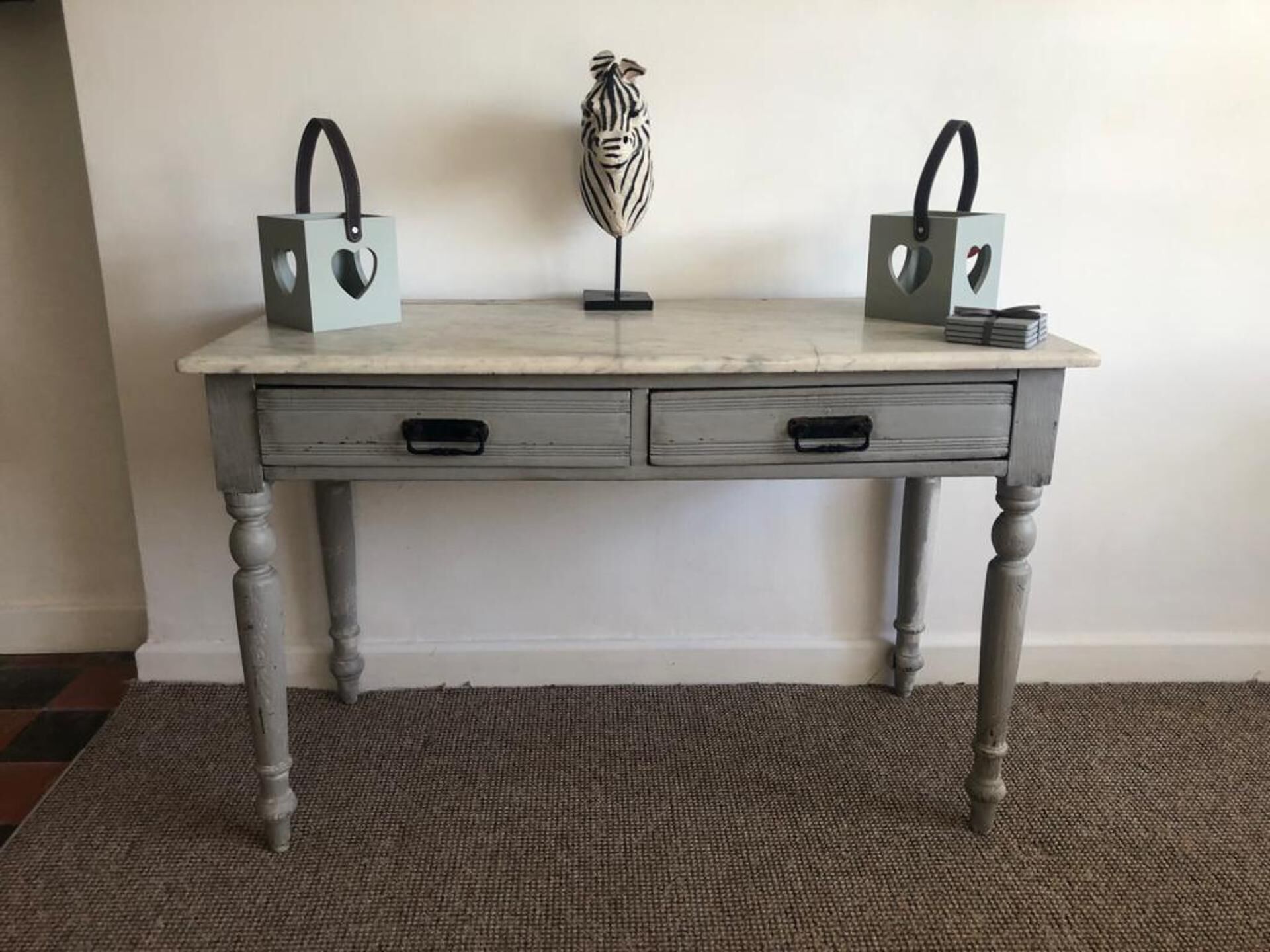 Un bureau de style vintage, doté de deux tiroirs et d’un plateau en marbre.