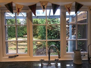 A kitchen with a window overlooking a garden, a vintage faucet, and a flower pot on the windowsill. - Charming Country Cottage in a Peaceful Location (Malpas)