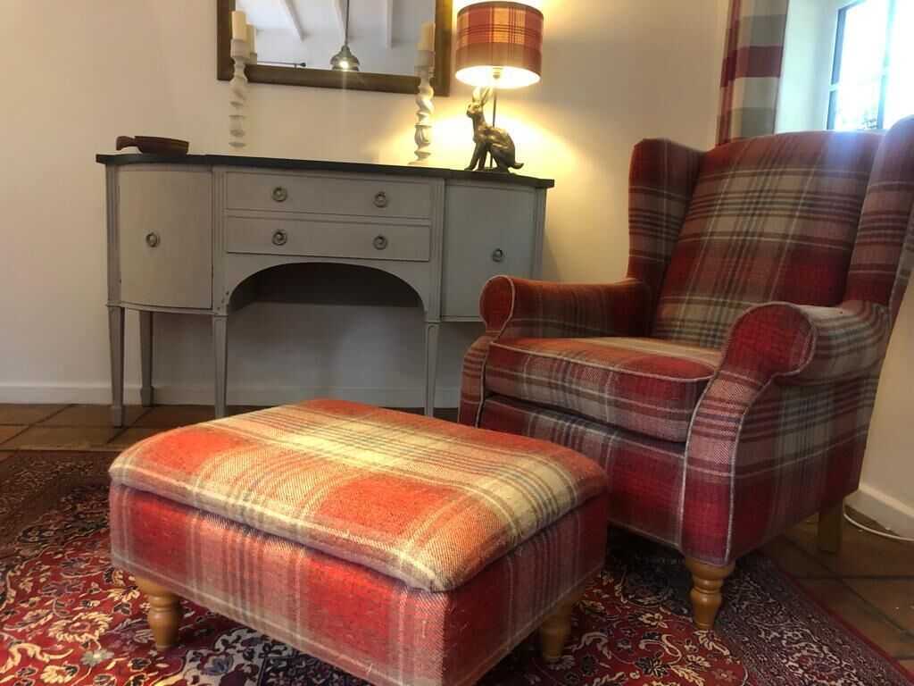 Een gestreept fauteuil en voetenbankje in een kamer met een bureau en lamp.