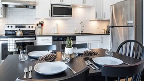 A modern kitchen with white cabinets, stainless steel appliances, and a dining table set for four.