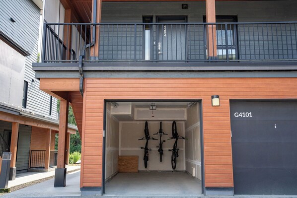 A modern building with a garage door labeled G4101, a wooden facade, and a balcony with a black railing.