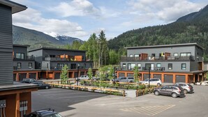 A modern hotel with multiple floors, parking area, and mountain views.