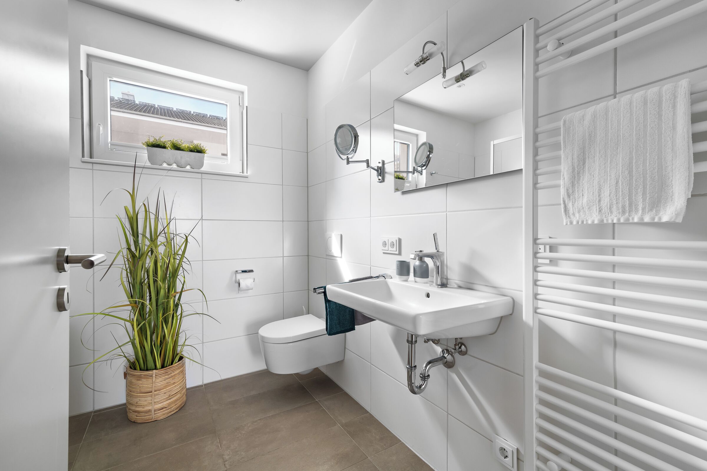 A modern bathroom with a toilet, sink, and towel rack.