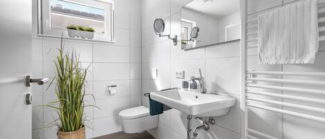 A modern bathroom with a toilet, sink, and towel rack.