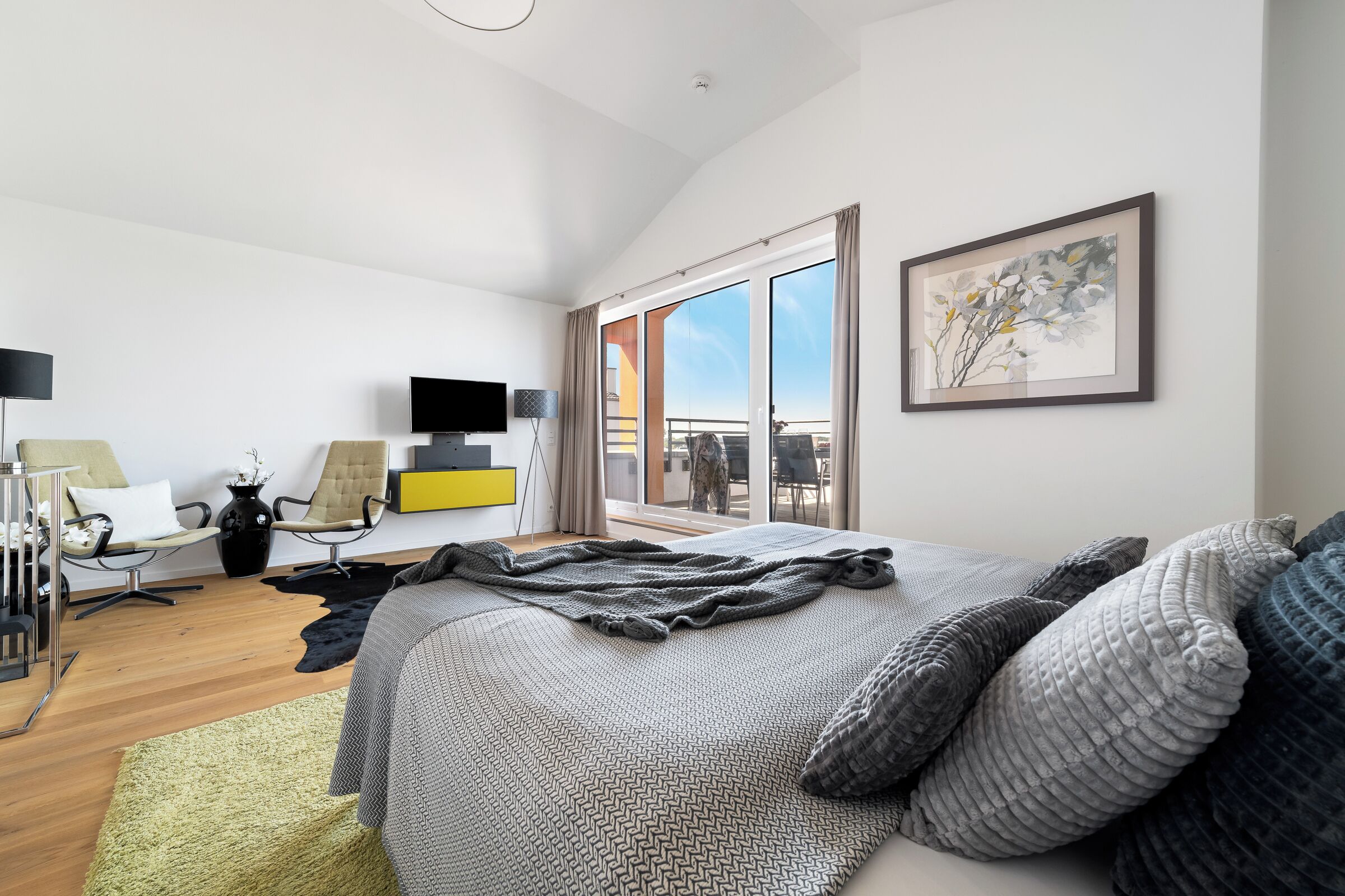 Ein modernes Hotelzimmer mit einem großen Bett, einem Flachbildfernseher, einem Schreibtisch und einem Balkon mit Blick.