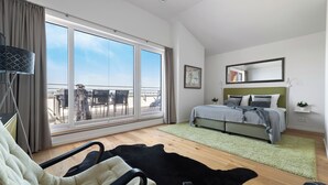 Une chambre à coucher moderne avec une grande fenêtre, un lit, un tapis vert et une chaise noire et blanche.