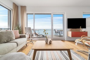 Una sala de estar moderna con un sofá, un sillón, una mesa de centro y un televisor de pantalla plana.
