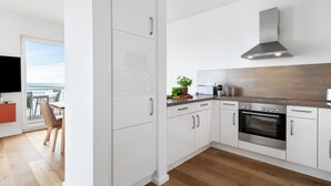 A modern kitchen with white cabinets, a stainless steel range hood, and an oven. - "Ocean Waves" Baltic Sea vacation with a 3-minute walk to the beach, fireplace and sea view (Olpenitz)