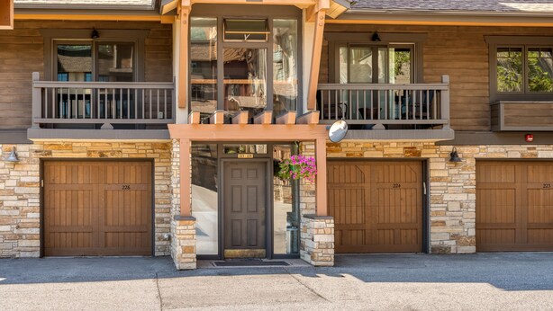 A two-story building with a balcony, a garage door, and a stone facade. - Close to the Slopes! Pool & Hot Tubs! Winter Shuttle! (Steamboat Springs)