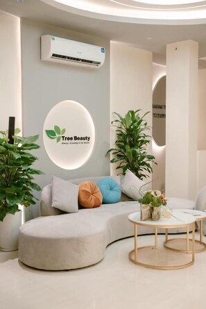 A modern lounge area with a curved sofa, a round table, and potted plants. - Bay Luxury Hanoi Boutique Hotel - No 9 Nguyen Truong To (Hanoi)