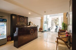 A reception desk with a logo, a refrigerator, and a sign for 'CHALCEDONY' in the background. - Bay Luxury Hanoi Boutique Hotel - No 9 Nguyen Truong To (Hanoi)