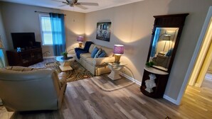 Un salon comprenant un canapé, un fauteuil, un téléviseur et des lampes décoratives.