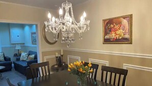 Un comedor con una araña, un jarrón de flores y un cuadro en la pared.