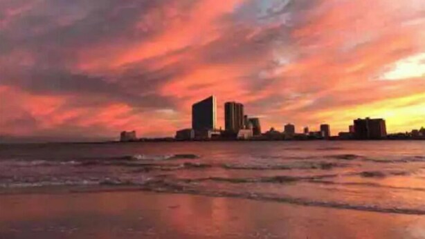 Un paisaje urbano costero al atardecer, con edificios silueteados contra un cielo lleno de color.