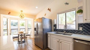 A modern kitchen with a stainless steel refrigerator, white cabinetry, and a black and white backsplash. - 4-min to Kierland- Heated Pool & Outdoor Dining, Scottsdale Gem (Scottsdale)