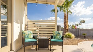 An outdoor patio with wicker chairs and a table, palm trees, and a clear sky. - 4-min to Kierland- Heated Pool & Outdoor Dining, Scottsdale Gem (Scottsdale)