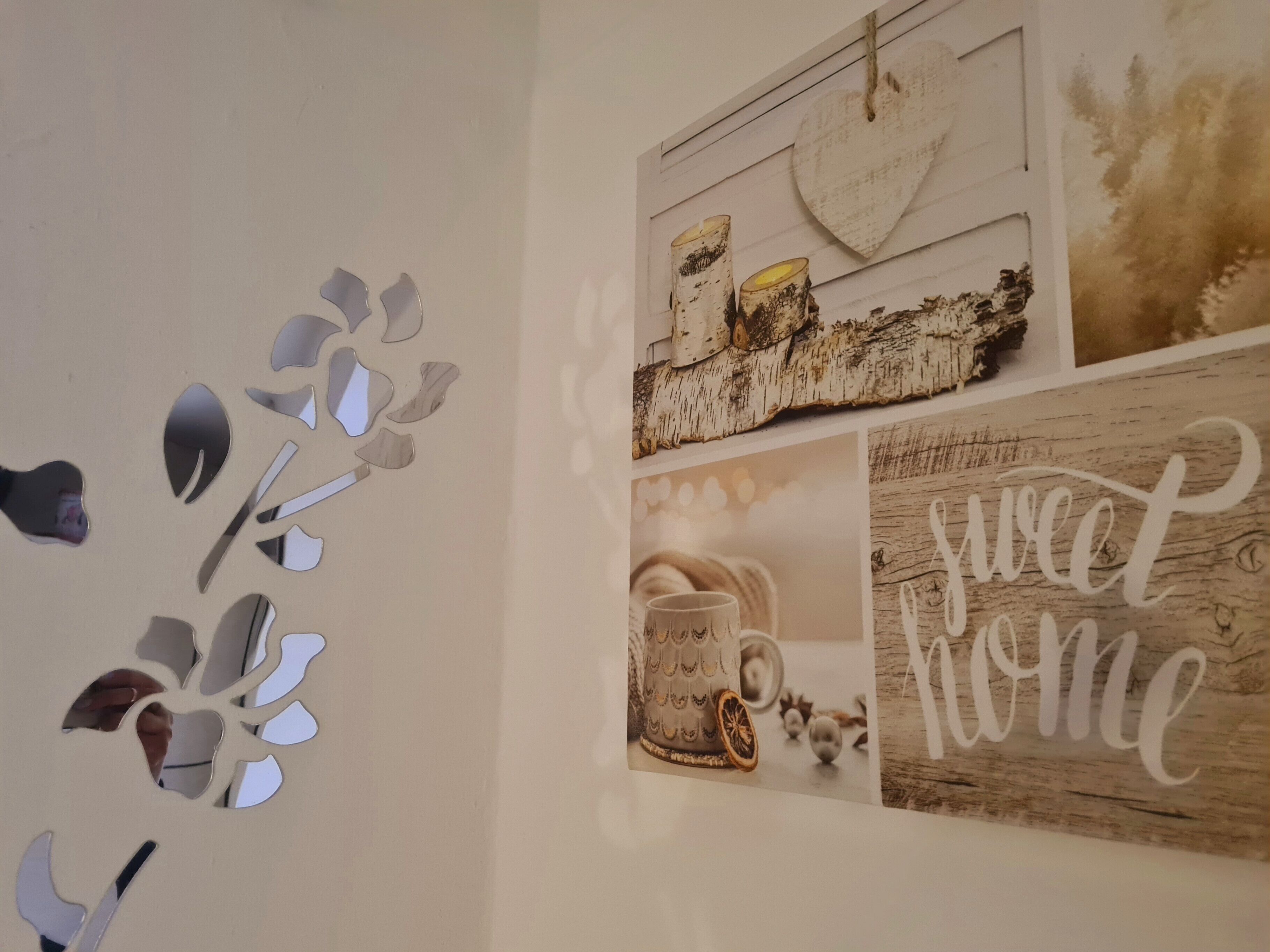 A wall with a decorative mirror arrangement and a collage of images including a 'sweet home' sign.