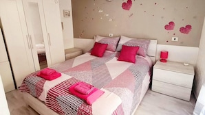 Une chambre à coucher comprenant un lit, des tables de chevet, une armoire et une décoration murale en forme de cœur.