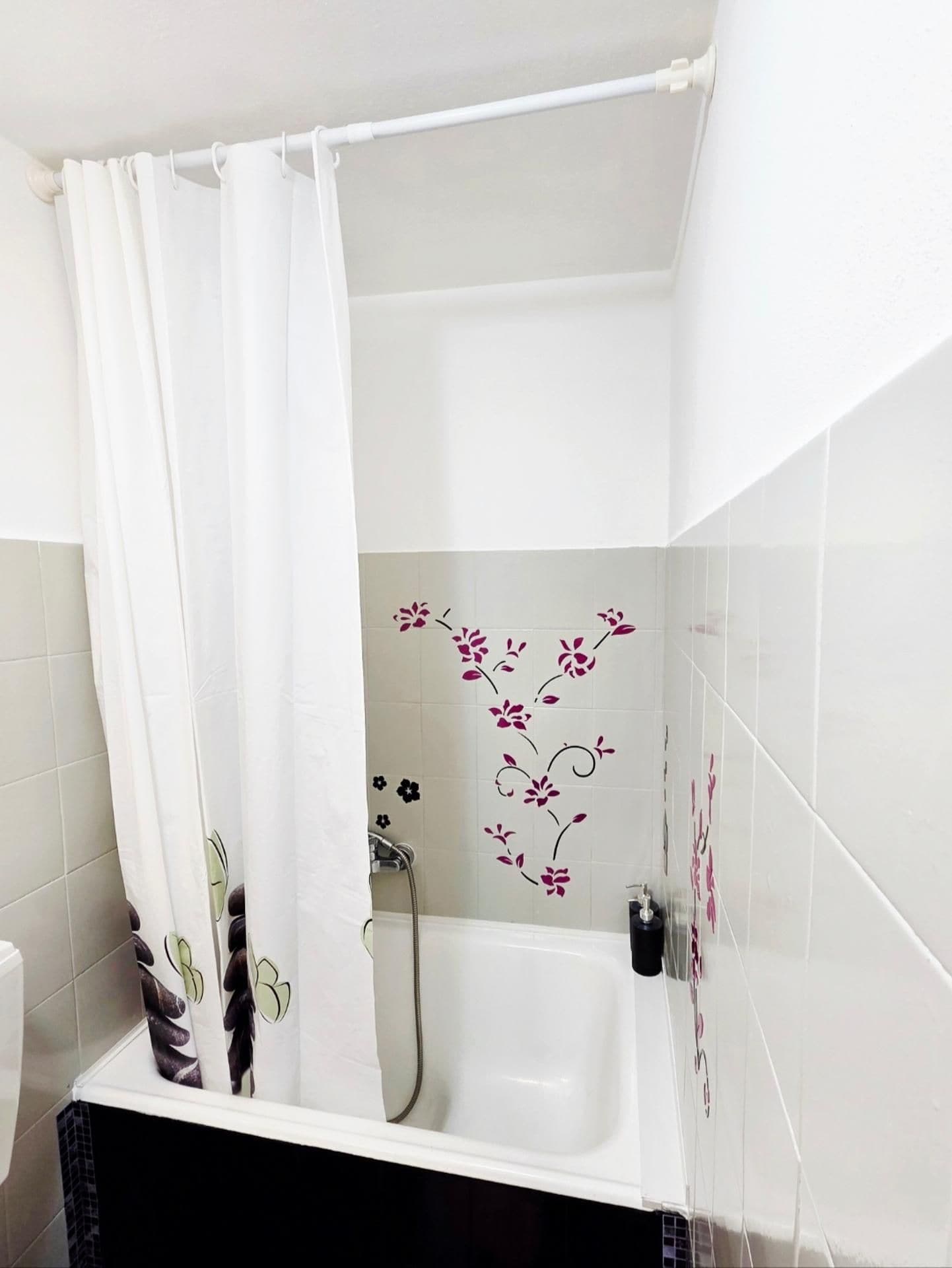 Un baño con bañera, cortina de ducha y paredes con azulejos.