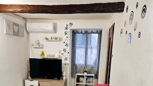 Un salon équipé d’un téléviseur à écran plat, d’un canapé, d’une table à manger et d’une petite plante.